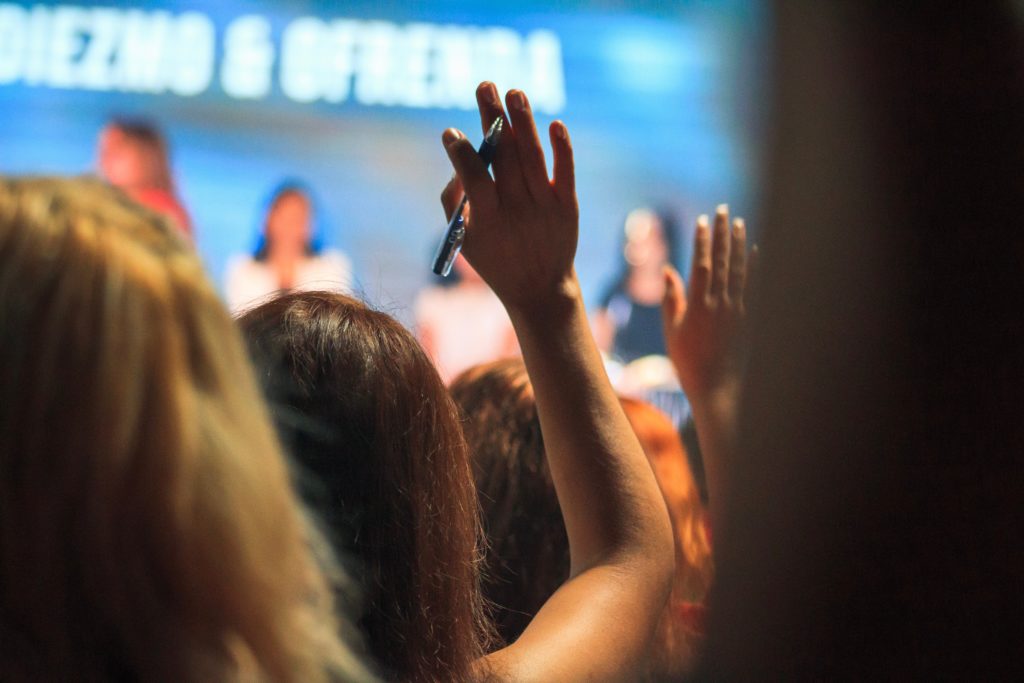 Image of woman's hand raised in audience watching a stage