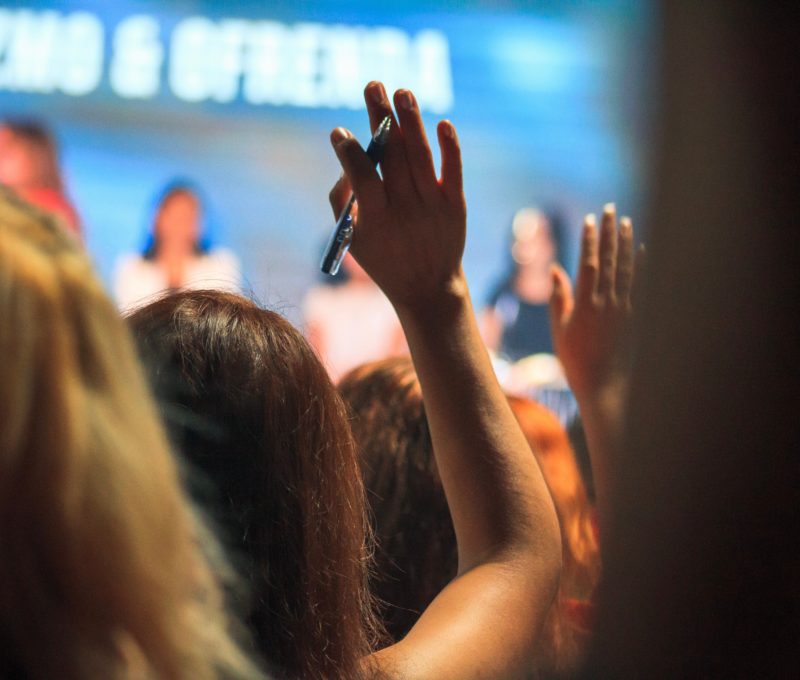 Image of woman's hand raised in audience watching a stage